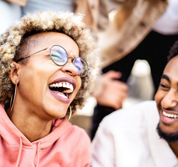 Multicultural couple on genuine laughter – Life style concept wi Multicultural couple on genuine laughter - Life style concept with happy multiracial friends having fun together out side - Trendy college students enjoying break time at campus - Warm vivid filter