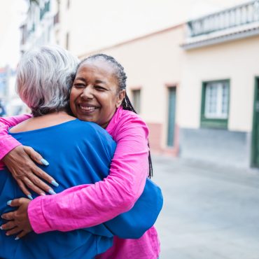 Multiracial senior women hugging each other - Diverse elderly friendship community - Focus on African woman face